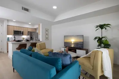 a living room with two blue couches and a kitchen at High-End 1BR Oasis | Walk to Ocean & 3rd Street in Los Angeles