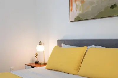 a bedroom with a bed with yellow pillows and a lamp at High-End 1BR Oasis | Walk to Ocean & 3rd Street in Los Angeles