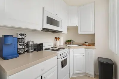 a kitchen with white cabinets and a stove top oven at SoCal Luxurious Apt Steps To The Beach & Pier in Los Angeles