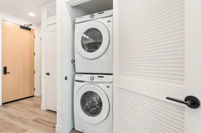 a laundry room with a washer and dryer next to a door at 5 Star 1BR Apartment w/ Free Parking & Fast WiFi in Los Angeles