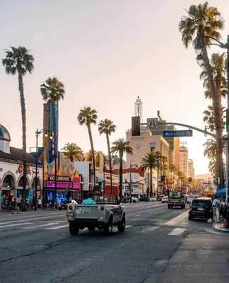 an old truck driving down a city street with palm trees at 5-star West Hollywood Living | Modern & Central in Los Angeles