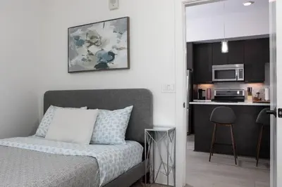 a bedroom with a bed and a kitchen with a microwave at West Hollywood Luxe | 2BR/2BA Resort Style in Los Angeles