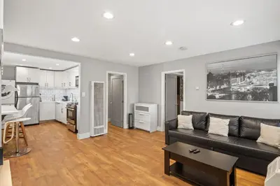 a living room with a black couch and a kitchen at Modern 1BR • Steps to Venice Beach in Los Angeles