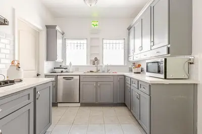a large kitchen with white cabinets and a microwave at Cozy 3-Bedroom Home in K-town Los Angeles in Los Angeles