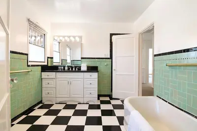 a bathroom with green tile and a tub and a sink at Spacious 4BR Spanish Villa In Hancock Park in Los Angeles