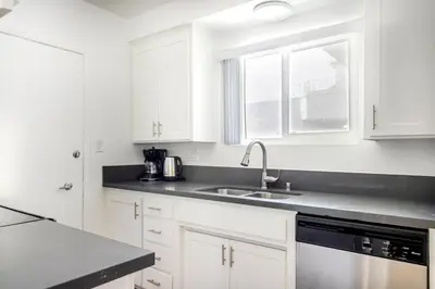 a white kitchen with white cabinets and a sink at Blueground Westwood balcony nr UCLA LAX-1397 in Los Angeles