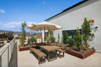 a patio with an umbrella and a table and benches at Blueground East Hollywood rooftop nr Griffith Park LAX-1337 in Los Angeles