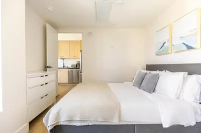 a white bedroom with a large bed and a kitchen at Blueground East Hollywood rooftop nr Hollywood Bowl LAX-1334 in Los Angeles