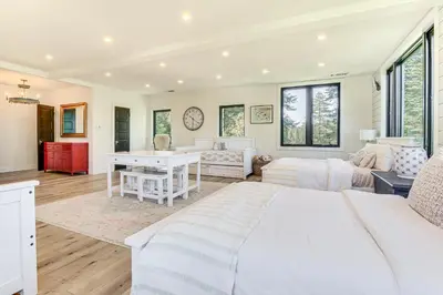 a bedroom with a white bed and a living room at Walk to Lake Arrowhead Village! Home with Lake Views in Lake Arrowhead