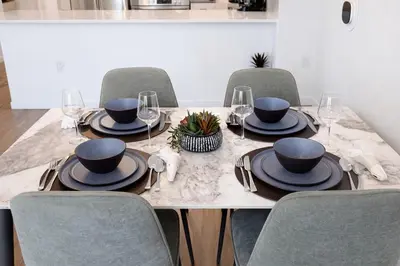 a dining room table with chairs and a table with plates and glasses at Penthouse Corner 3 Bedroom Condo with Large Private Balcony and Parking in Los Angeles