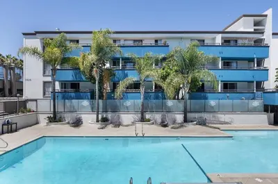 an apartment building with a swimming pool and palm trees at Modern West LA Studio with Pool, Gym & Parking in Los Angeles