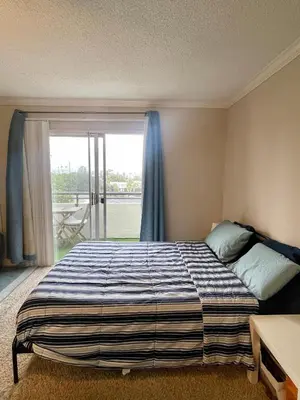 a bedroom with a bed and a large window at Modern West LA Studio with Pool, Gym & Parking in Los Angeles