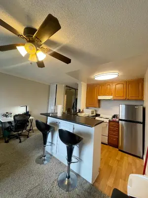 a kitchen with a ceiling fan and a kitchen island with bar stools at Modern West LA Studio with Pool, Gym & Parking in Los Angeles