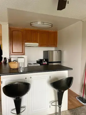 a kitchen with two black stools at a counter at Modern West LA Studio with Pool, Gym & Parking in Los Angeles