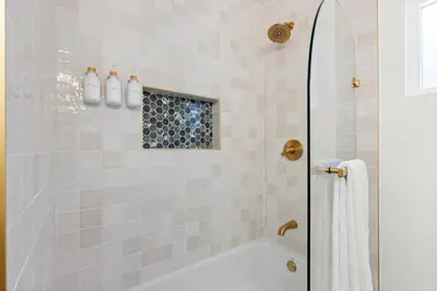 a bathroom with a shower with a white tub at NEW Remodeled Northridge 5 Bedroom Near CSUN & Sherwood Forest in Northridge