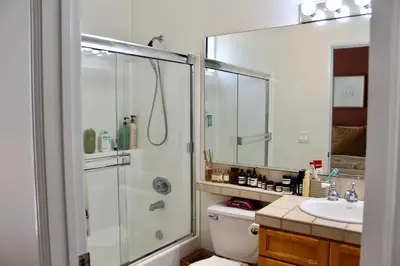 a bathroom with a shower and a toilet and a sink at Designer Light-Filled WeHo Condo in Los Angeles