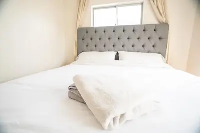 a white bed with a gray headboard and a window at Bright and Comfortable 2 Bedrooms with Views in Santa Monica in Los Angeles