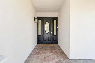 an empty hallway with a black door and a brick floor at Cozy & Bright Santa Clarita Retreat in Santa Clarita