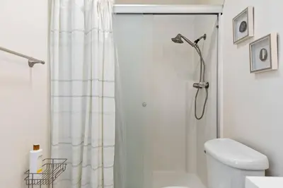 a white bathroom with a shower curtain and a toilet at Cozy & Bright Santa Clarita Retreat in Santa Clarita