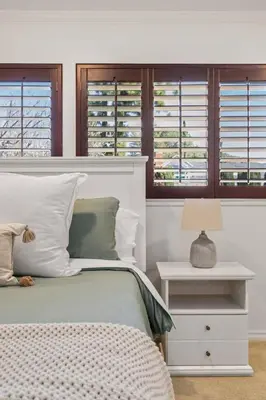 a bedroom with a bed and a nightstand and windows at Goode HOMES Stunning Home w/ Beautiful Backyard in Santa Clarita