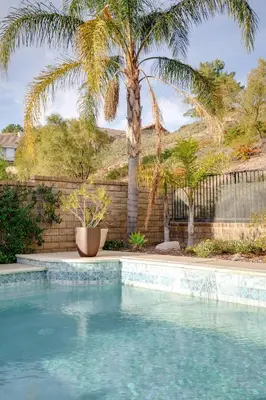 a swimming pool with a palm tree and a fence at GOODE.HOMES | Luxury Home w/ pool & lush gardens in Santa Clarita