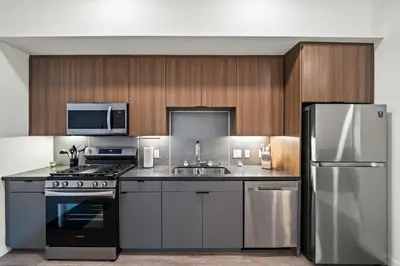 a kitchen with stainless steel appliances and wooden cabinets at Chic Downtown Stay Walk to Beach in Long Beach