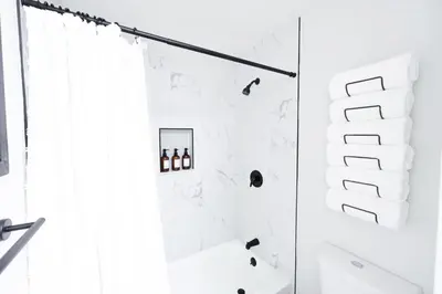 a white bathroom with a shower and a toilet at Family Friendly Southwest Bakersfield Retreat with Jacuzzi and Fenced Yard in Bakersfield