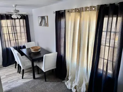 a dining room with a table and chairs and curtains at Unique apartment in Los Angeles