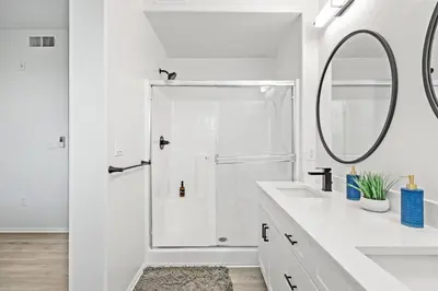 a white bathroom with a shower and a mirror at Cozy 3 BR Apartment | Near Disney in Placentia