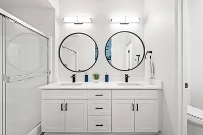 a white bathroom with two sinks and two mirrors at Cozy 3 BR Apartment | Near Disney in Placentia