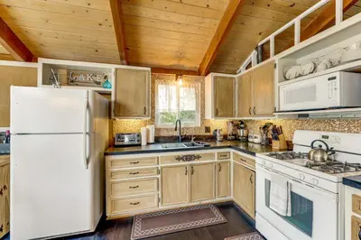 a kitchen with wooden cabinets and a white refrigerator at 2 Mi to Lake Arrowhead! Mtn-View Hideaway with Deck in Cedar Glen