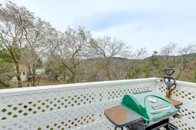 a green lawn mower sitting on a white fence at 2 Mi to Lake Arrowhead! Mtn-View Hideaway with Deck in Cedar Glen
