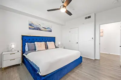 a bedroom with a blue bed and a ceiling fan at Newly Remodeled 3BR Apt | Mins to Disney | Arcade in Placentia