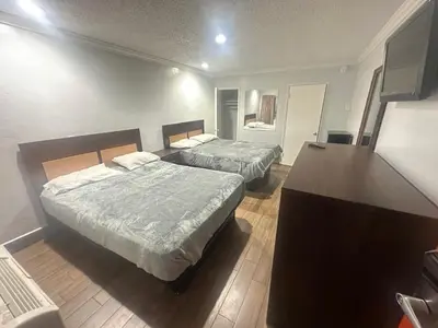 a hotel room with two beds and a desk at Heritage Inn in Pomona