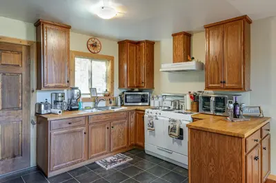 a kitchen with wooden cabinets and a white stove top oven at PMC Mountainside Cabin Hit the Trails, Play Pool! in Pine Mountain Club