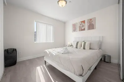 a white bedroom with a bed and a window at Niagara Haven Unit 103 in Burbank