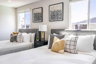 two beds in a bedroom with two windows at Modern 4BR Stay Premium Beds & Full Kitchen in Burbank