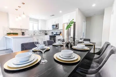a dining room with a table with plates and wine glasses at Modern 4BR Stay Premium Beds & Full Kitchen in Burbank