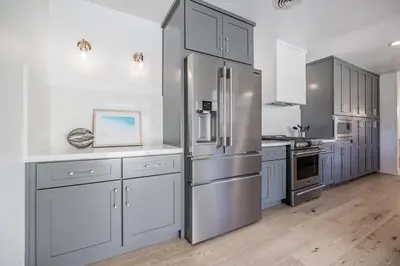 a kitchen with a stainless steel refrigerator and white cabinets at Cozy Modern Haven w Soothing Ambience & Pool in Fullerton