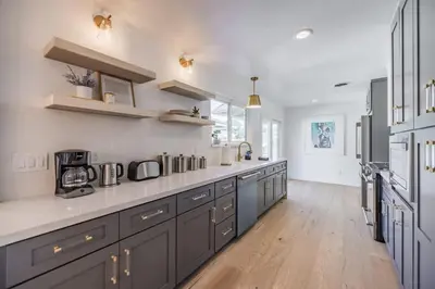 a large kitchen with gray cabinets and wooden floors at Cozy Modern Haven w Soothing Ambience & Pool in Fullerton