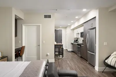 a bedroom with a bed and a kitchen with a refrigerator at Casa Clementine - 10 min to SNA&Beach Plus Free Parking in Orange