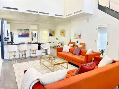 a living room with orange couches and a kitchen at The Gallery Spacious 2BD 2BA with Two King Beds in Los Angeles