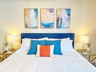 a bedroom with a blue and white bed with four paintings at Spacious 2 BD with 2 King Beds Walk to Pier & Beach in Los Angeles