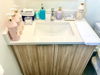 a bathroom counter with a sink and bottles of soap at 2 KING BED SUITE WALK to BEACH,PIER, PROMENADE in Los Angeles