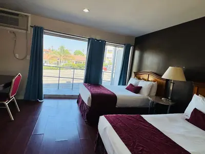 a hotel room with two beds and a window at Holiday Lodge in Los Angeles