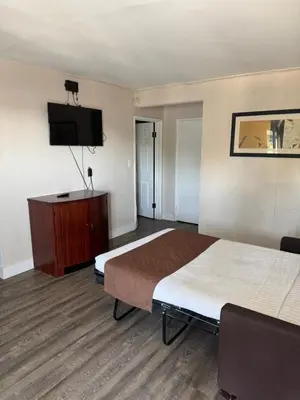 a hotel room with a bed and a flat screen tv at Holiday Lodge in Los Angeles