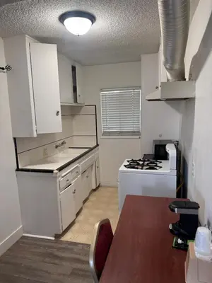 a kitchen with white cabinets and a table and a stove at Holiday Lodge in Los Angeles
