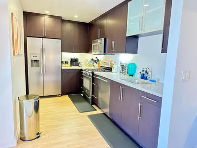 a kitchen with stainless steel appliances and wooden cabinets at 5 Star Location with City Views 2BD 2BA with King Beds in Los Angeles