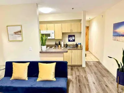 a living room with a blue couch and a kitchen at Heart of DT SM Studio, Walk To Beach & Pier in Los Angeles