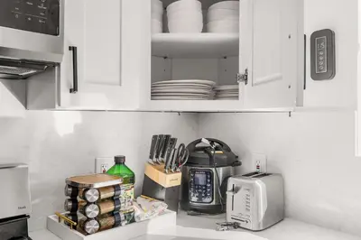a kitchen with white cabinets with plates and a microwave at Marbella Lane - Cityside Haven w Touch of Charm in Compton